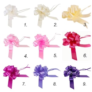 May include: Nine different colours of satin ribbon bows with tails. The colours are ivory, pink, hot pink, purple, and lavender.