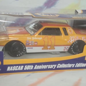 May include: A 1970s NASCAR collector's edition diecast car in its original packaging. The car is yellow and orange with the number 11 on the side. The packaging includes the NAPA logo and text that reads "NASCAR 50th Anniversary Collectors Edition."