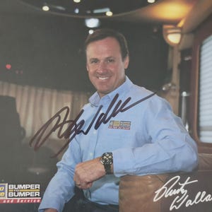 May include: A signed photograph featuring a man in a light blue button-down shirt. The photo includes the signatures "Rusty Wallace" and another signature. The image also includes the text "ALL PRO Auto Value BUMPER Auto Parts and Service."