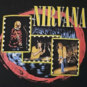 Könnte beinhalten: Schwarzes T-Shirt mit dem Bandnamen "NIRVANA" in gelben Blockbuchstaben und einem roten und schwarzen Kreisdesign. Das Shirt hat drei gerahmte Bilder der Band bei einem Auftritt.