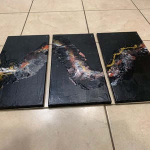 May include: A three-piece abstract art canvas set with black, gold, white, and pink paint. The canvas is textured and has a modern, contemporary style.