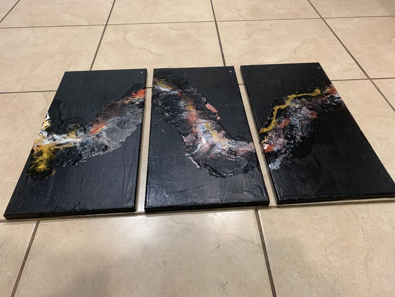 May include: A three-piece abstract art canvas set with black, gold, white, and pink paint. The canvas is textured and has a modern, contemporary style.