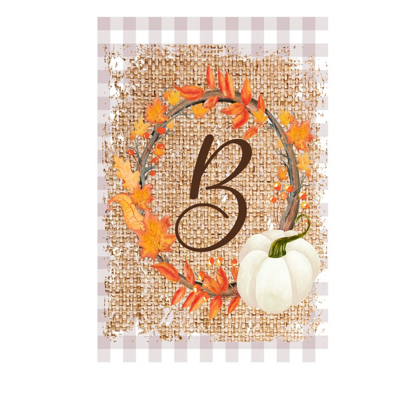 Op de afbeelding: Een herfstontwerp met de bruine letter "B" omcirkeld door een krans van oranje en gele herfstbladeren en bessen. Een witte pompoen staat onder de letter. De achtergrond heeft een jute textuur met een lichtbruin en wit geblokt patroon.