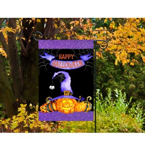 Può includere: Una bandiera da giardino di Halloween viola e nera con un cappello da strega su una zucca e il testo "Happy Halloween".