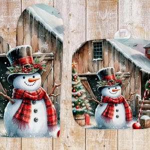 Può includere: Due presine per pentole a forma di guanto e quadrata con un motivo a scacchi rosso e bianco di pupazzo di neve. La scena invernale rappresenta un fienile, un albero di Natale e la neve.