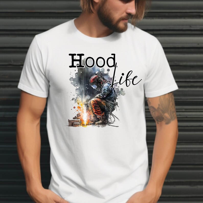 May include: White t-shirt with a black graphic of a welder wearing a welding mask and holding a welding torch. The text "Hood Life" is printed in black above the graphic.