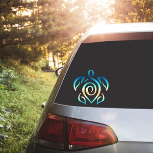 May include: A blue and green gradient vinyl decal of a stylized turtle design on the back window of a silver car.
