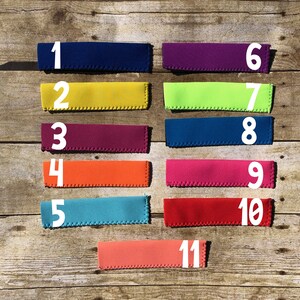 May include: A collection of eleven colorful beverage insulators, each with a different solid color. The insulators are numbered 1 through 11, with colors including navy blue, yellow, purple, orange, teal, and red.