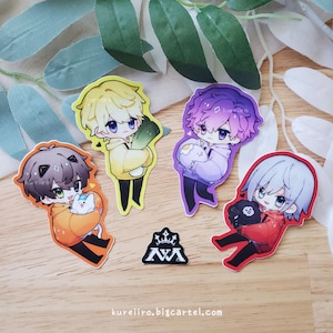 May include: Four anime-style character stickers in various colors, each holding a small animal or vegetable. The stickers are on a wooden surface with green leaves. A small black and white logo is also present. The website address kureiiro.bigcartel.com is at the bottom.