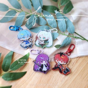 May include: Four acrylic keychains featuring chibi-style anime characters from Frieren: Beyond Journey's End. The characters have distinct hair colours including blue, white, purple, and red, and each is attached to a coloured plastic lobster clasp.