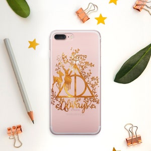 May include: A gold iPhone case with a floral design and the Hogwarts crest. The crest is surrounded by a deer and the word "Always" is written below it.