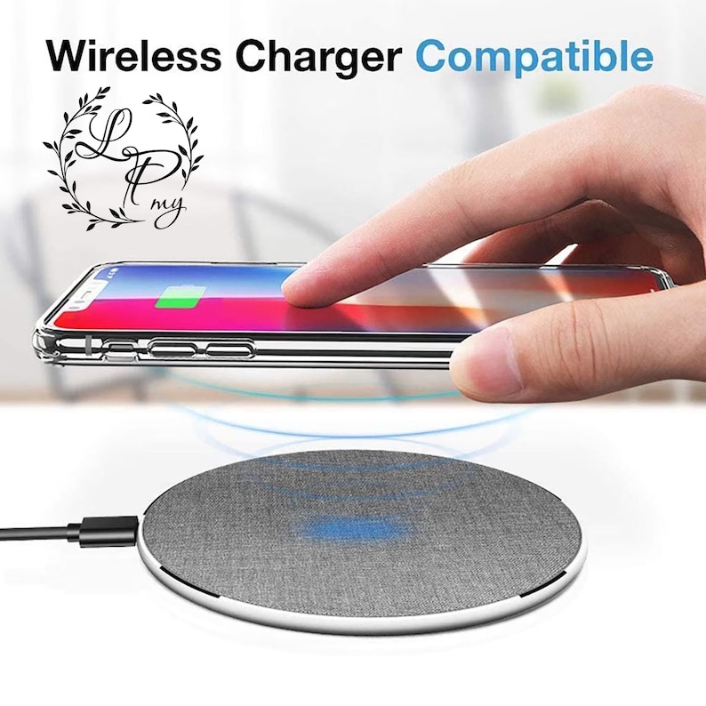May include: A gray wireless charging pad with a fabric top and a white border. A clear phone case with a phone inside is being placed on the charging pad.