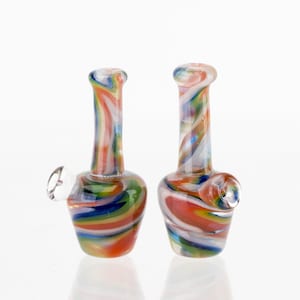 Peut inclure: Deux pipes à eau en verre coloré avec un motif tourbillonnant de rouge, orange, jaune, vert, bleu et blanc. Chaque pipe a une base bulbeuse, un long col et un petit bol clair sur le côté.