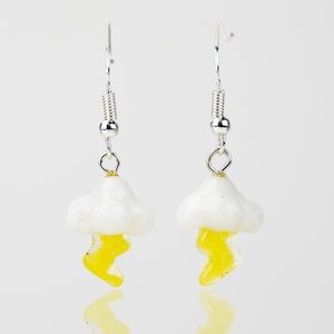 May include: A pair of silver dangle earrings with white cloud and yellow lightning bolt charms.