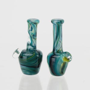 May include: A set of three ceramic mugs with a speckled, cream-colored glaze. Each mug features a different hand-painted floral design in shades of blue, green, and yellow. The mugs have a simple, rounded shape and a comfortable handle.