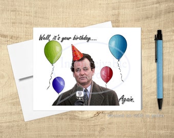 Può includere: Un biglietto di auguri di compleanno con Bill Murray che indossa un cappello da festa e tiene un microfono. Il biglietto ha il testo "Well, it's your birthday... Again." e presenta palloncini colorati.