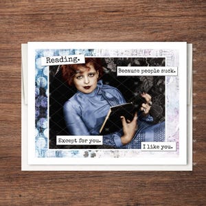 May include: A greeting card featuring a vintage-style photograph of a person with reddish hair wearing a blue high-neck top and holding an open book. The text reads: Reading. Because people suck. Except for you. I like you. The card has a blue border.