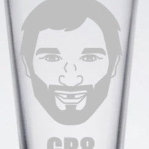 May include: A clear glass pint glass with a white etched image of a man's face with a beard and the text "GR8" below the image.