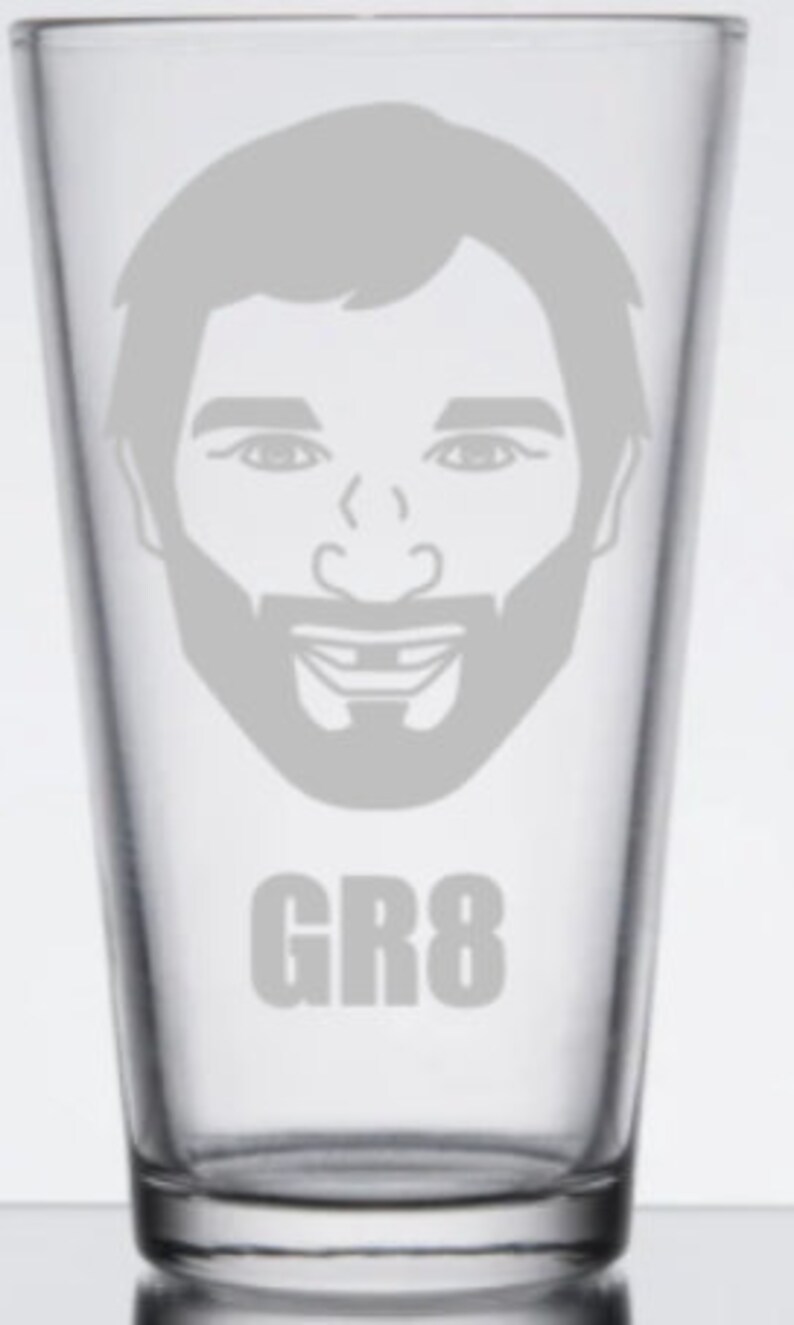 May include: A clear glass pint glass with a white etched image of a man's face with a beard and the text "GR8" below the image.