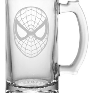 Puede incluir: Una jarra de cerveza de vidrio transparente con un dise&ntilde;o grabado en blanco de la m&aacute;scara de Spider-Man.