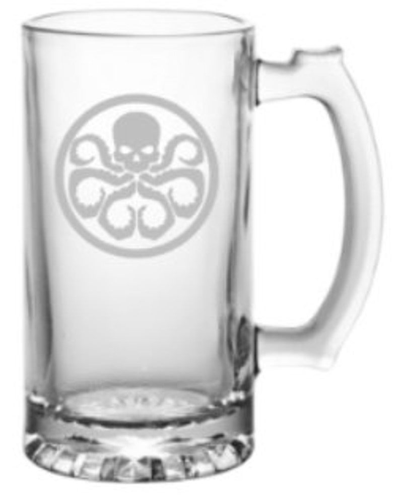 May include: A clear glass beer stein with a handle. The stein features an etched design of a skull with tentacles, a symbol often associated with the fictional organization HYDRA.