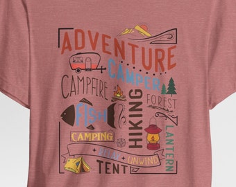 May include: A pink t-shirt with a graphic design featuring the words "Adventure Camper" and illustrations of a camper, tent, campfire, fish, lantern, and forest. The text also includes the words "Hiking, Relax, Unwind, Camping, Forest, Lantern, Tent".