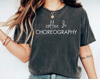 Op de afbeelding: Een donkergrijs T-shirt met de tekst "coffee & choreography" in wit gedrukt op de voorkant.