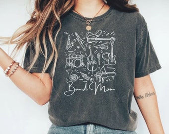May include: A dark gray t-shirt with a white graphic design of musical instruments and the text "Band Mom".