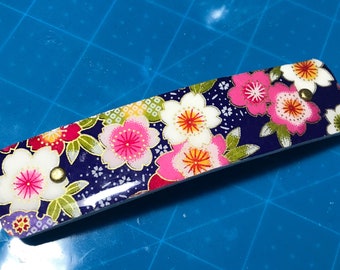 Handmade French clip hair barrette for medium to thick hair. Measures 4.5x1. Multicolored cherry blossoms on blue background