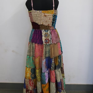 Könnte beinhalten: Ein langes, mehrfarbiges Patchworkkleid mit einem taillierten Oberteil und einem fließenden Rock. Das Kleid ist aus verschiedenen Stoffen gefertigt, darunter Seide, Baumwolle und Samt. Das Kleid hat einen rosa Träger und ein gerafftes Oberteil.