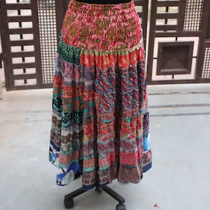 Puede incluir: Una falda larga multicolor con un diseño de patchwork. La falda está hecha de diferentes telas y tiene una variedad de patrones, incluyendo florales, paisley y geométricos. La falda está fruncida en la cintura y tiene un dobladillo con volantes.