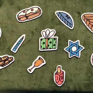 May include: A collection of colorful, hand-drawn stickers featuring Jewish holiday symbols. Includes a dreidel, Star of David, menorah, challah bread, coins, and a gift box with a bow. The stickers are set against a green background.