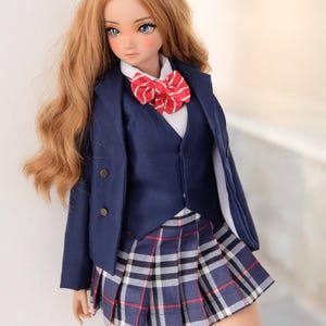以下が含まれることがあります： 青いブレザー、赤い蝶ネクタイのついた白いシャツ、青い格子柄のスカート、グレーのニーハイソックスを履いた人形です。