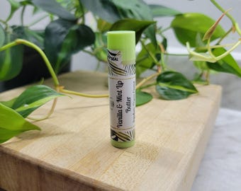 May include: A green lip balm tube with a white label that says "Vanilla & Mint Lip Butter" and "Handmade Sugar Cane Coconut".
