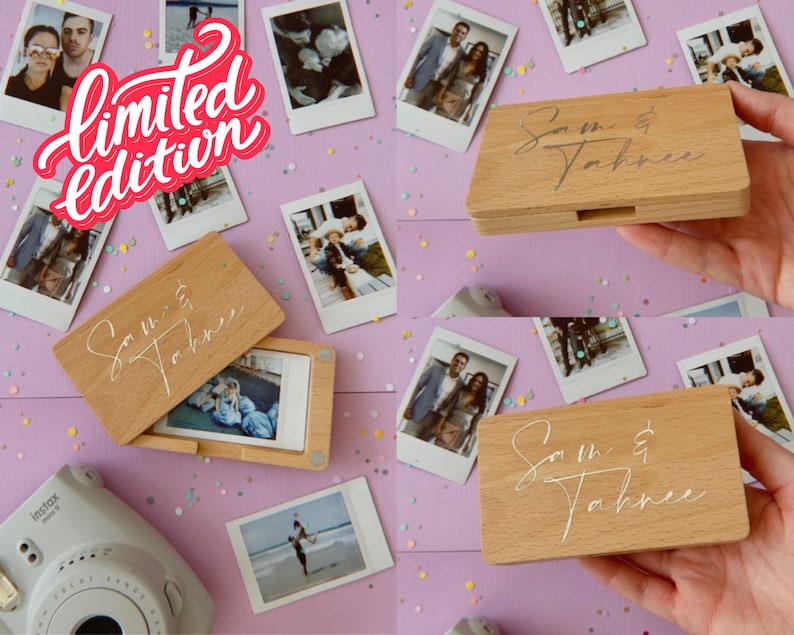 Op de afbeelding: Een houten doos met een scharnierend deksel, gepersonaliseerd met de tekst "Sam & Tahnee". De doos is gevuld met instant foto's en is omringd door meer instant foto's op een roze oppervlak.