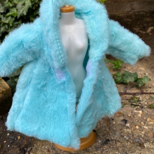 May include: A light blue faux fur coat with a hood. The coat is open and the lining is visible.