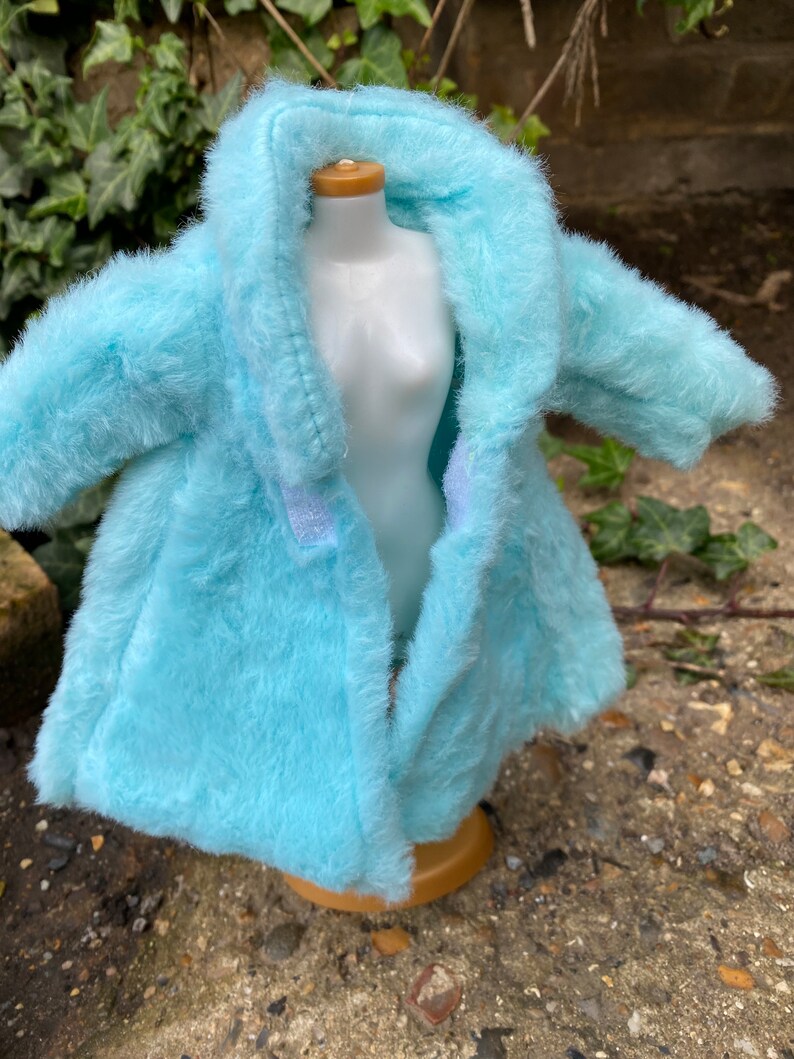 May include: A light blue faux fur coat with a hood. The coat is open and the lining is visible.