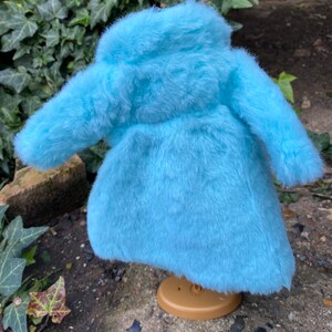 May include: A light blue faux fur coat with a high collar and long sleeves.