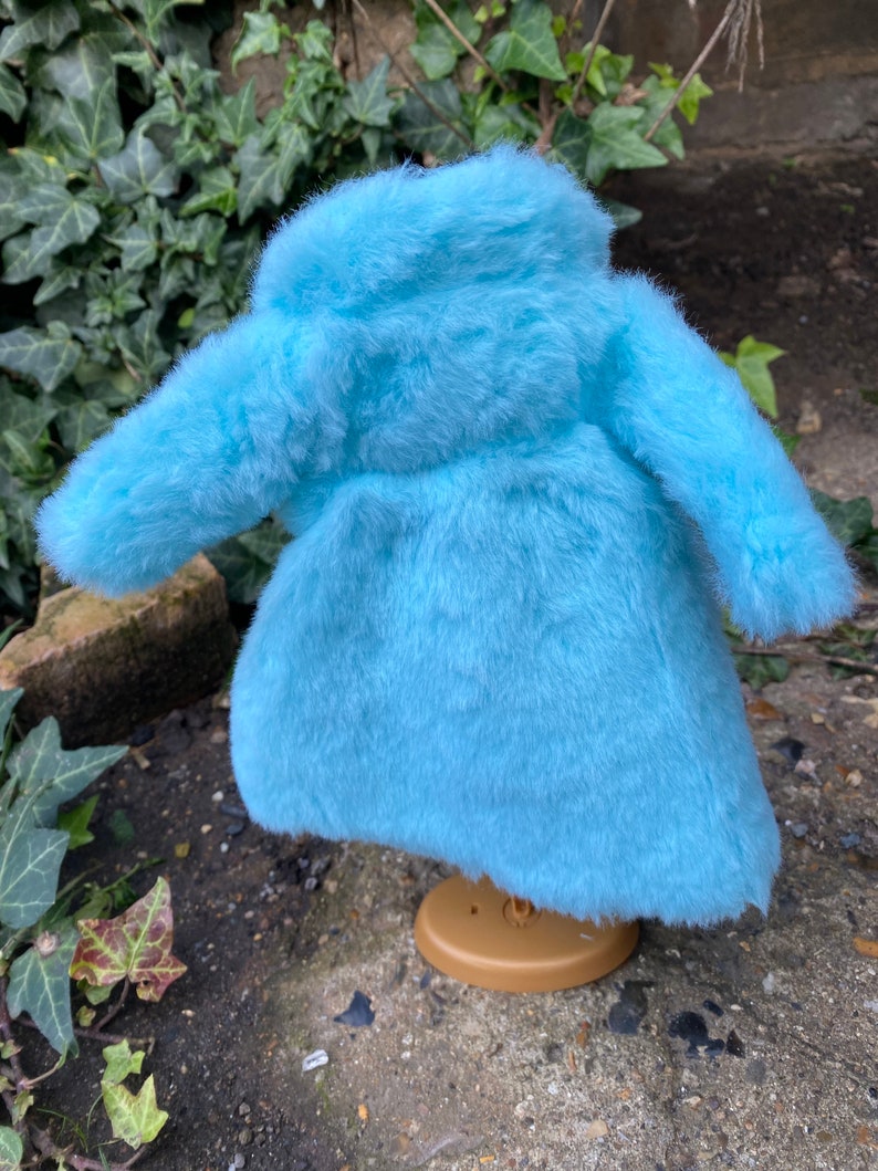 May include: A light blue faux fur coat with a high collar and long sleeves.