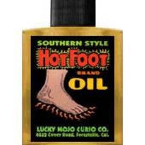 May include: A small bottle of amber-colored "Southern Style Hot Foot Brand Oil" with a black cap. The label features a cartoon illustration of a foot with flames underneath it. The text "Lucky Mojo Curio Co. 622 Cedar St. Berkeley, Cal." is printed on the label.