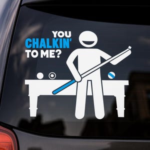 May include: White vinyl decal featuring a stick figure holding a pool cue, with the text "YOU CHALKIN' TO ME?" in white and blue. The design includes a pool table and balls, perfect for car windows or other smooth surfaces.