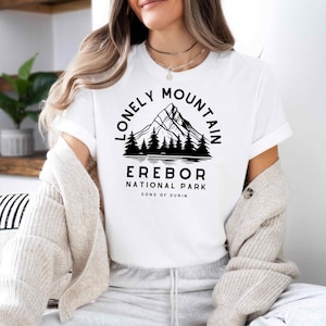 Könnte beinhalten: Weißes T-Shirt mit schwarzer Bergketten-Grafik und dem Text "Lonely Mountain Erebor National Park Sons of Durin". Das T-Shirt hat kurze Ärmel und einen Rundhalsausschnitt.