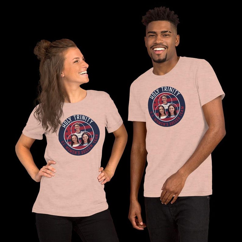以下が含まれることがあります： 2人ともヘザーグレーのTシャツを着ており、紺色の円形のグラフィックには「Holy Trinity Women's Soccer Team」と書かれています。