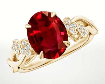May include: A gold ring with a large, oval-cut, deep red gemstone. The band features small, diamond-set floral designs. The ring's design is elegant and suitable for special occasions. The gemstone is a vibrant, rich red colour.