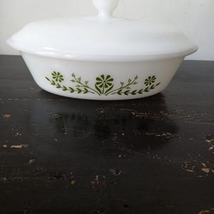 May include: White oval casserole dish with a lid, featuring a green floral design around the rim.