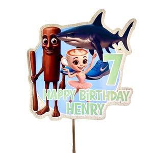 May include: A vibrant birthday cake topper with a cartoon shark, a coffee cup character, and a cinnamon stick figure. The topper includes the text "HAPPY BIRTHDAY HENRY" and the number "7". The design has a glittery border and is mounted on a wooden stick.