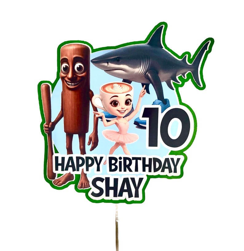 May include: A vibrant cake topper featuring a cartoon shark, a ballerina in a coffee cup, and a wooden figure with a bat. The text "HAPPY BIRTHDAY SHAY" and the number "10" are displayed on the topper.