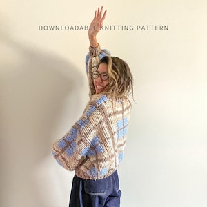 May include: A person wearing a blue, beige, and white plaid knitted cardigan. The image includes the text "DOWNLOADABLE KNITTING PATTERN" and "THE KNITTY GRIDDY CARDIGAN BY BRENDA LAM".