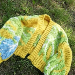 Peut inclure: Un cardigan en tricot jaune, vert et bleu avec une fermeture boutonn&eacute;e. Le cardigan est ample et de longueur courte.