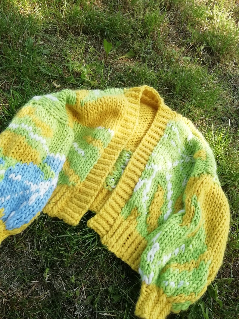 Peut inclure: Un cardigan en tricot jaune, vert et bleu avec une fermeture boutonn&eacute;e. Le cardigan est ample et de longueur courte.